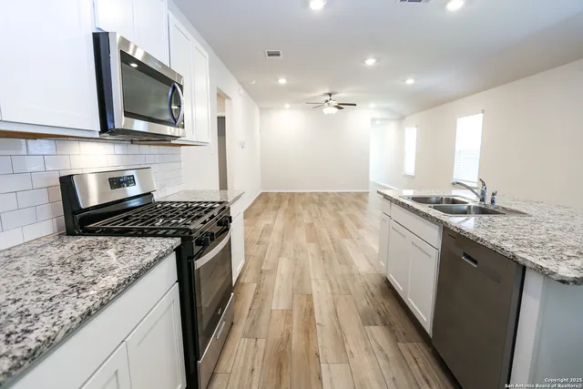 a kitchen with granite countertop stainless steel appliances sink stove microwave and cabinets