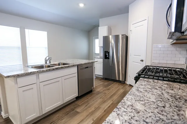 a kitchen with stainless steel appliances granite countertop a refrigerator and a sink