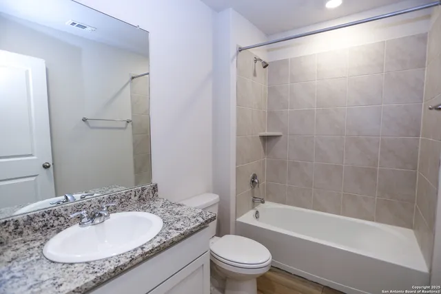 a bathroom with a granite countertop sink toilet mirror and shower