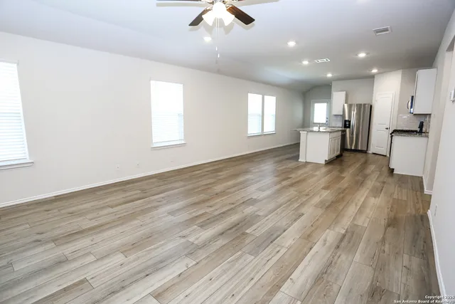 a view of a kitchen with a sink a ceiling fan and wooden floor