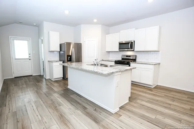 a kitchen with a refrigerator stove top oven and sink