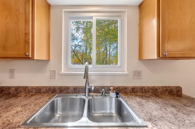 a kitchen with stainless steel appliances granite countertop a refrigerator a sink dishwasher a stove and a dining table with wooden floor