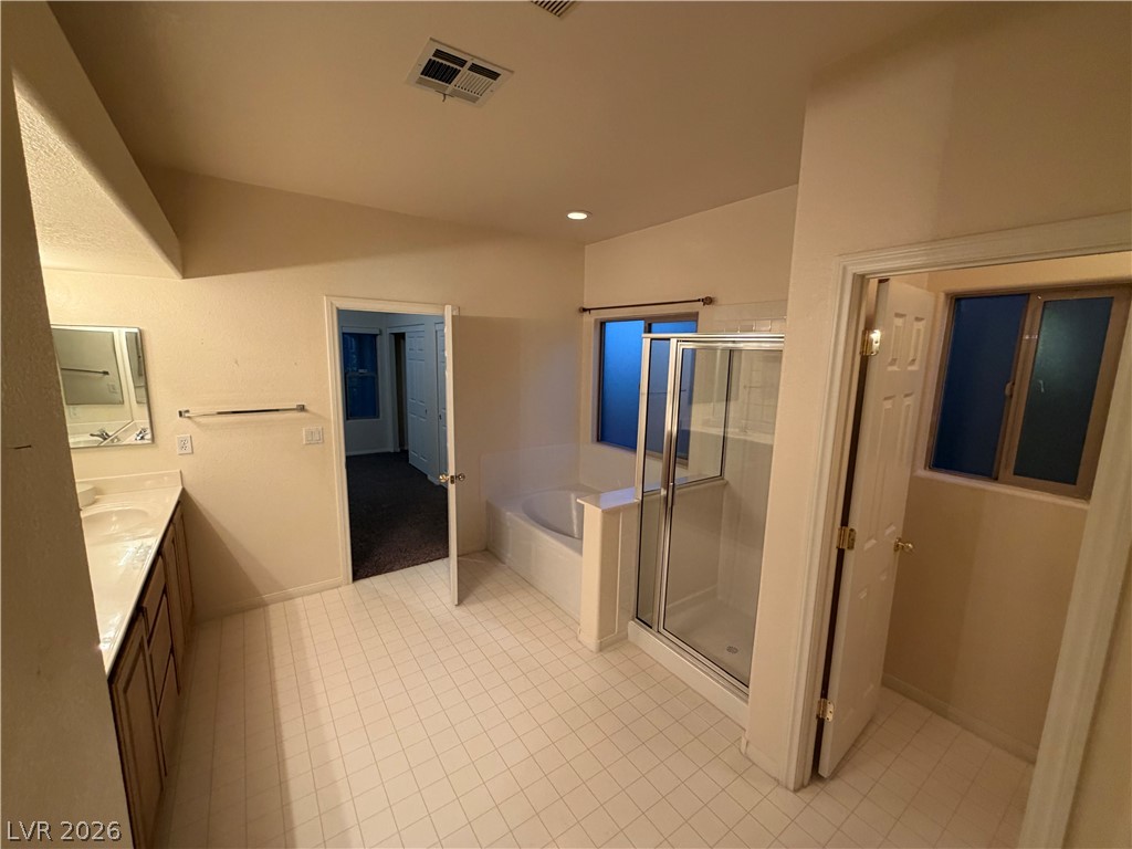 7629 Rory Court Las Vegas, NV 89129 - Photo 12 of 25 This spacious primary bathroom features dual vanities and a separate soaking tub and glass-enclosed shower.