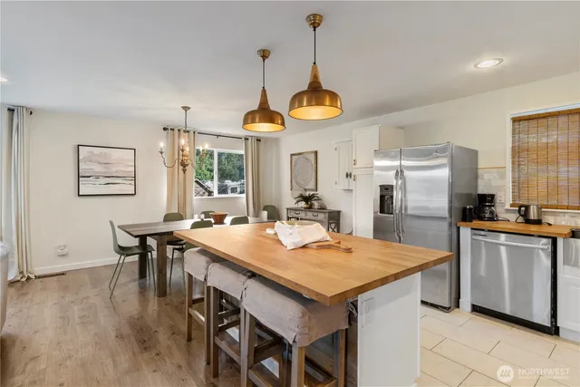 a kitchen with stainless steel appliances kitchen island granite countertop a table chairs and a refrigerator