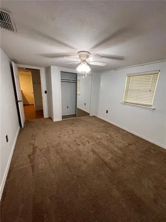 an empty room with a ceiling fan and window