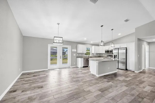 a large kitchen with a refrigerator and wooden floor