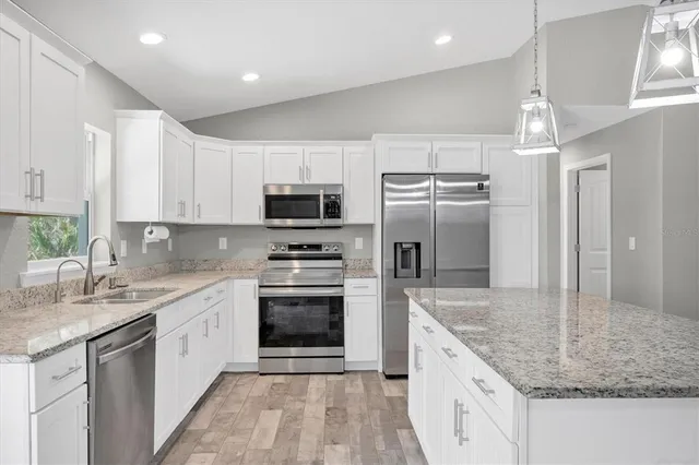 a kitchen with stainless steel appliances granite countertop a sink stove microwave and refrigerator