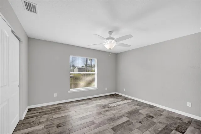 an empty room with a chandelier fan and windows