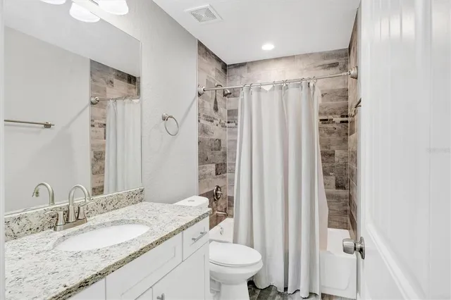 a bathroom with a granite countertop sink toilet and shower