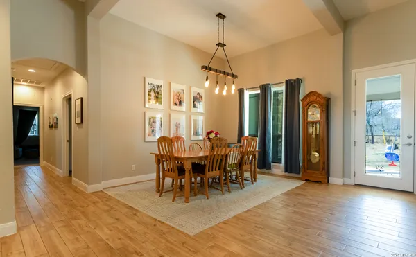 a dining hall with stainless steel appliances kitchen island granite countertop a dining table chairs and a refrigerator