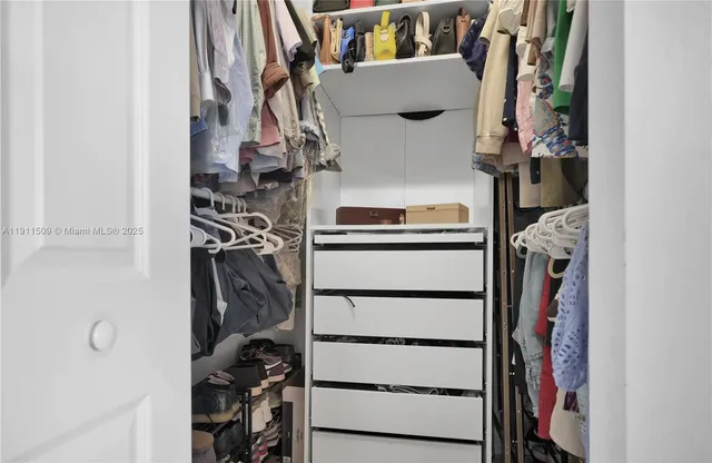 a view of walk in closet with clothes and shoes