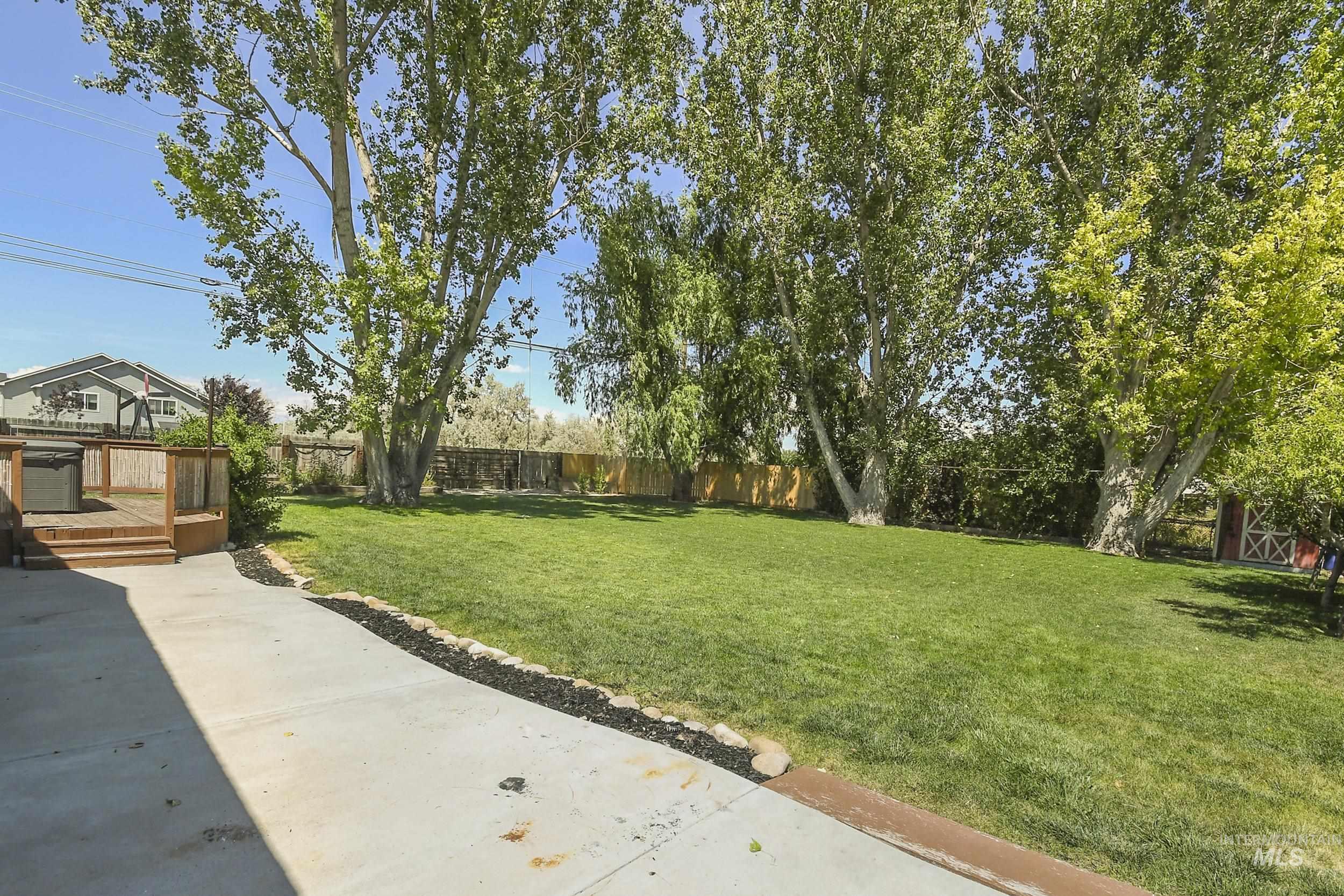 1108 East Ustick Road Caldwell, ID 83607 - Photo 27 of 30 Expansive backyard featuring a manicured lawn, established shade trees, and a wooden deck with steps