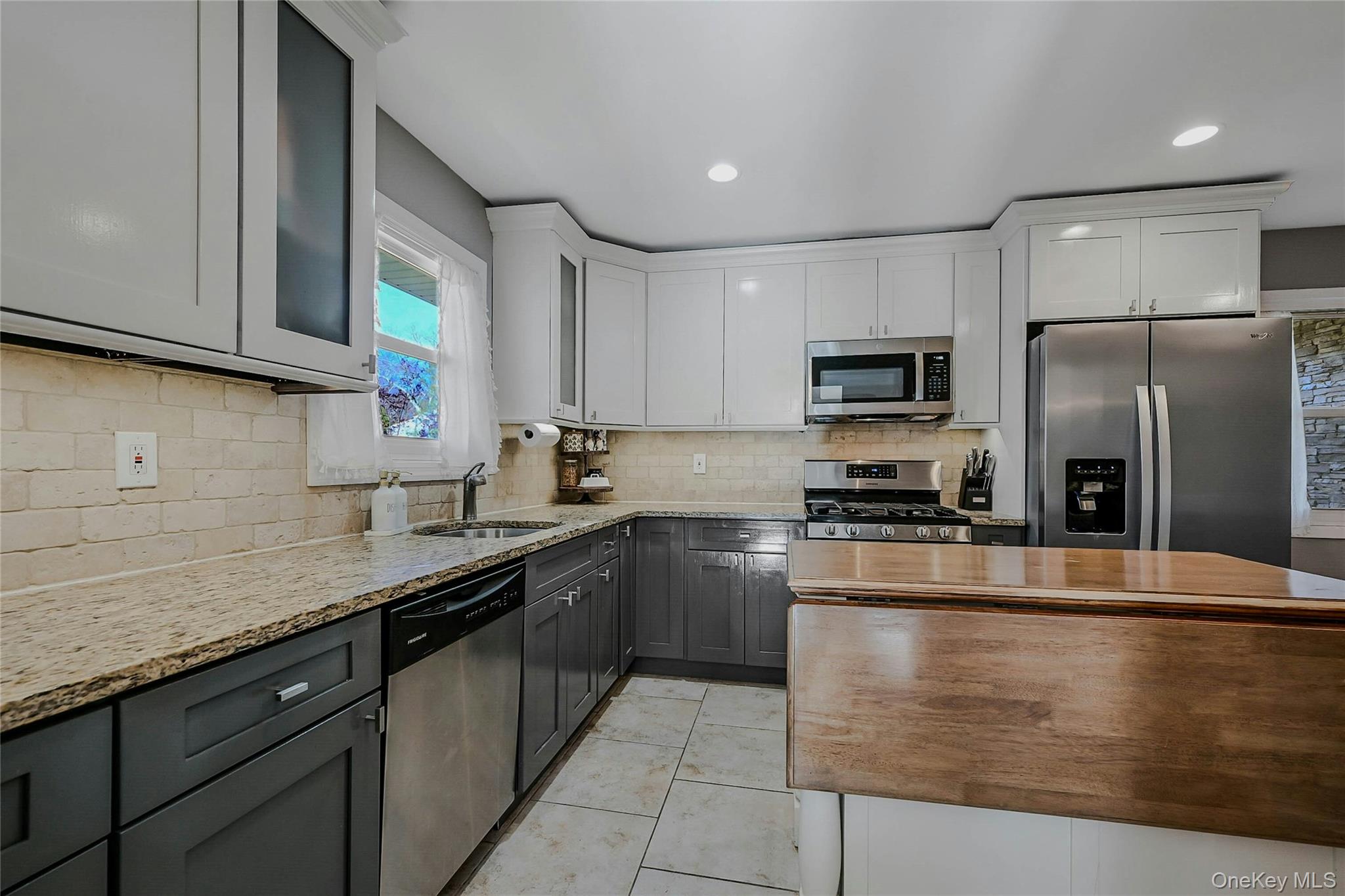4 Park Road Rocky Point, NY 11778 - Photo 15 of 38 a kitchen with stainless steel appliances granite countertop a sink a stove top oven a refrigerator and dishwasher with wooden floor