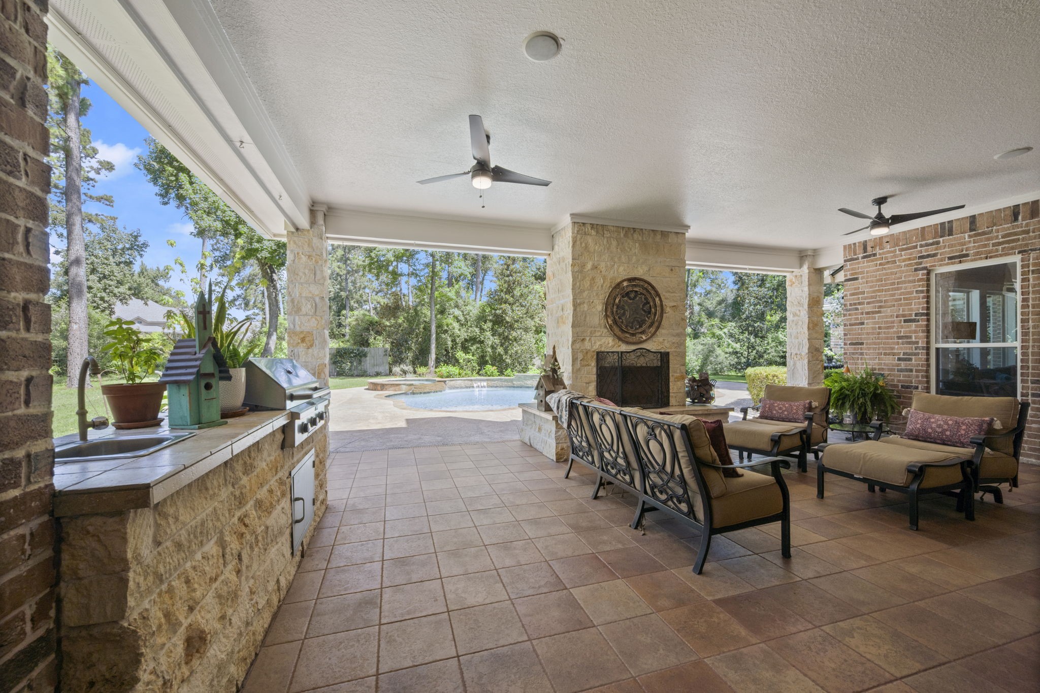 4106 Angling Lane Spring, TX 77386 - Photo 11 of 50 Spacious covered patio featuring a cozy outdoor fireplace, comfortable seating, and a built-in grill, all overlooking a lush backyard with a sparkling pool.