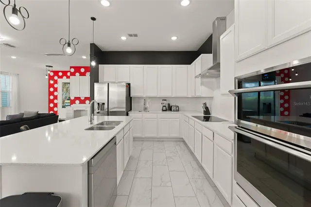 a large white kitchen with stainless steel appliances kitchen island granite countertop a sink and cabinets