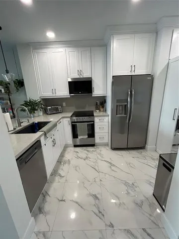 a kitchen with stainless steel appliances granite countertop a sink a stove a refrigerator a microwave and cabinets