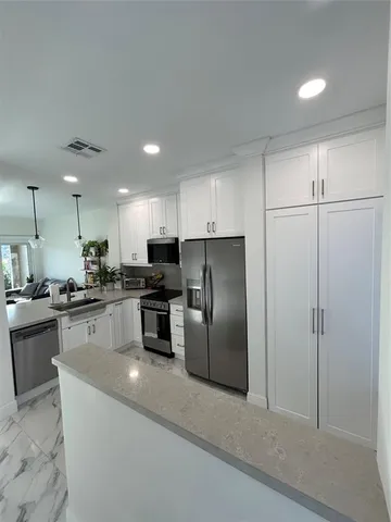 a kitchen with stainless steel appliances granite countertop a refrigerator a sink a stove top oven a counter space and cabinets