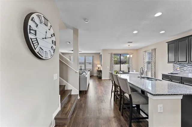 a kitchen with stainless steel appliances granite countertop wooden cabinets a refrigerator a stove a sink and a dining table with wooden floor