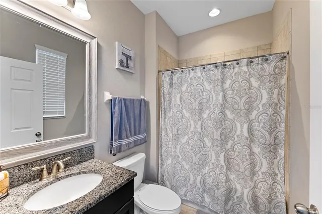 a bathroom with a granite countertop sink a large mirror and a shower curtain