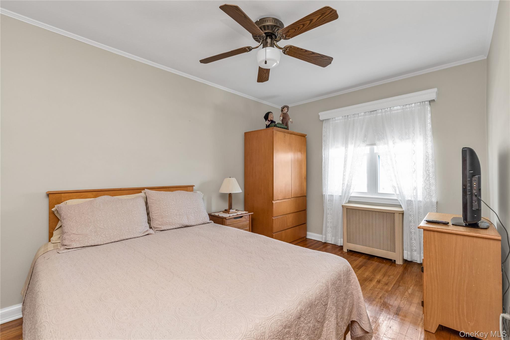 142-24 61st Road Queens, NY 11367 - Photo 11 of 18 Bedroom with radiator, crown molding, a ceiling fan, and wood finished floors