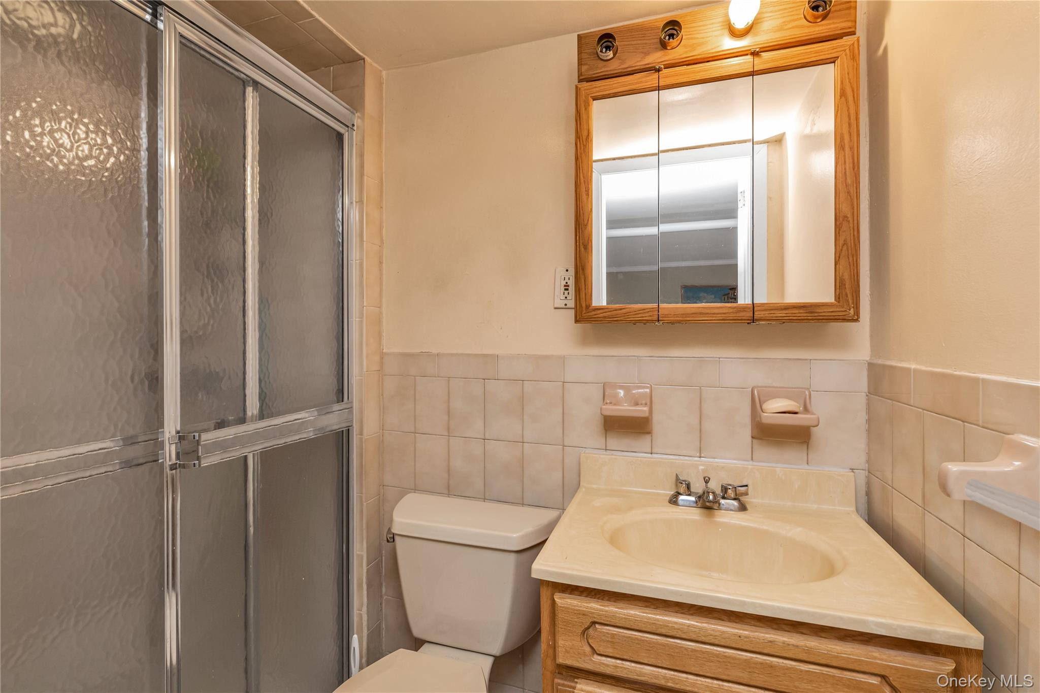 142-24 61st Road Queens, NY 11367 - Photo 14 of 18 Full bathroom with vanity, a stall shower, tile walls, and wainscoting