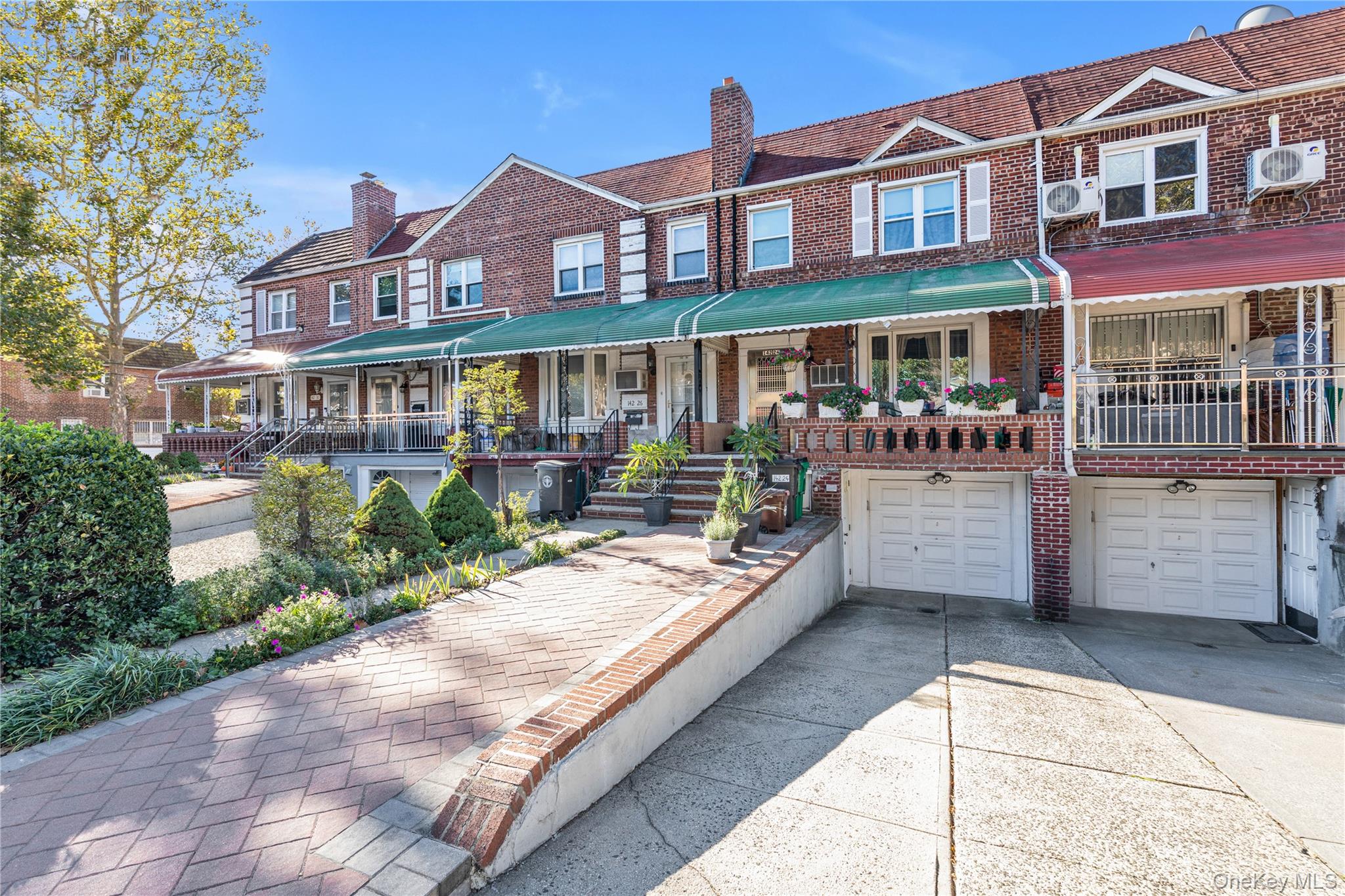 142-24 61st Road Queens, NY 11367 - Photo 17 of 18 View of front of house featuring a porch, brick siding, a chimney, driveway, and an attached garage