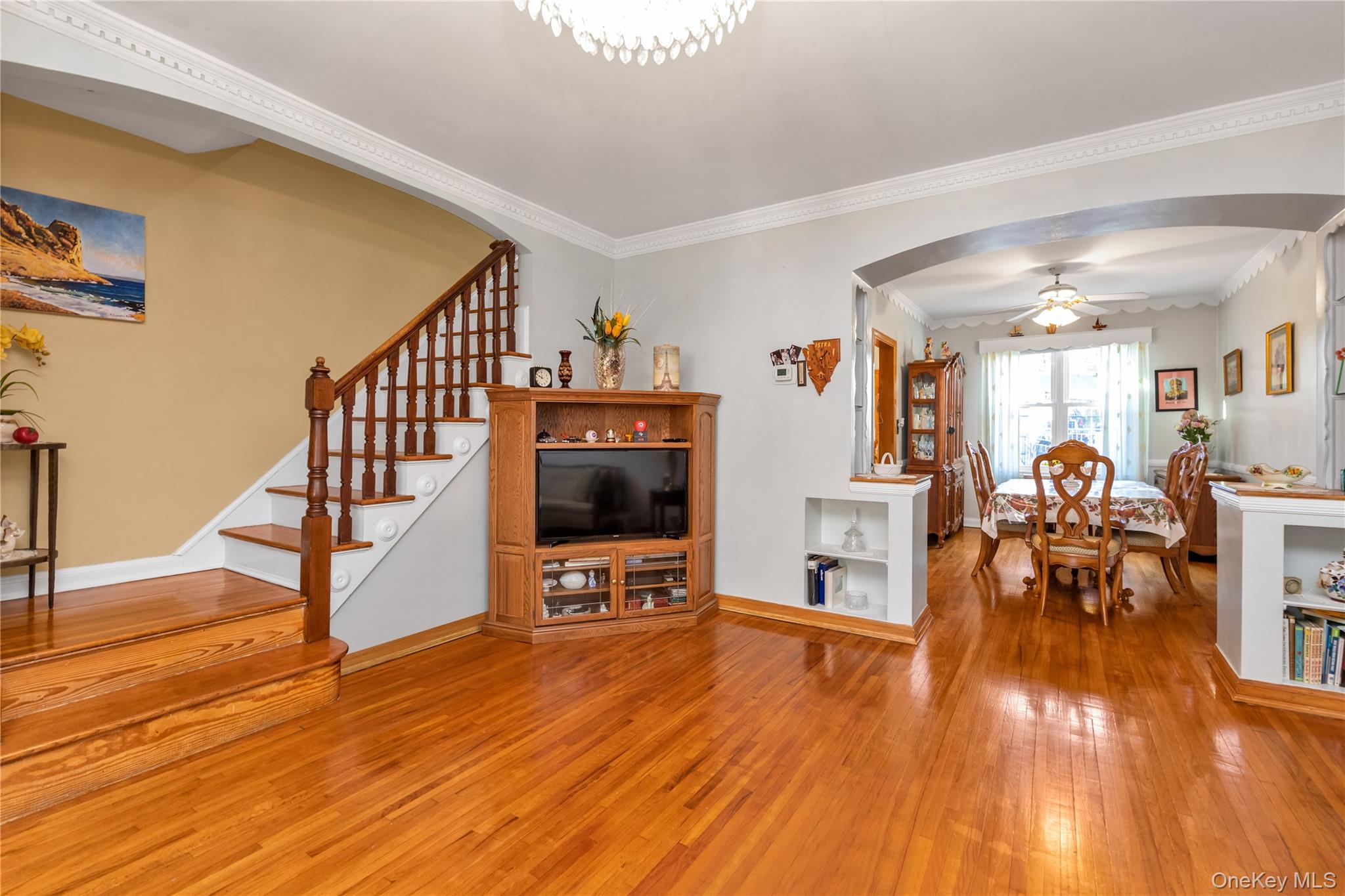 142-24 61st Road Queens, NY 11367 - Photo 3 of 18 Living room featuring light wood-type flooring, arched walkways, ornamental molding, stairway, and ceiling fan