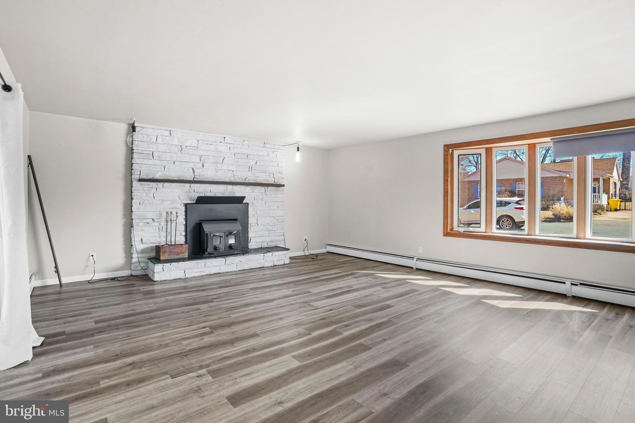 an empty room with wooden floor fireplace and windows