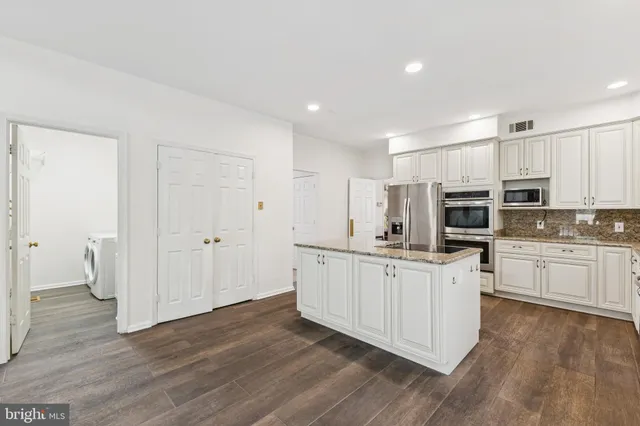 a kitchen with stainless steel appliances a white cabinets and wooden floor