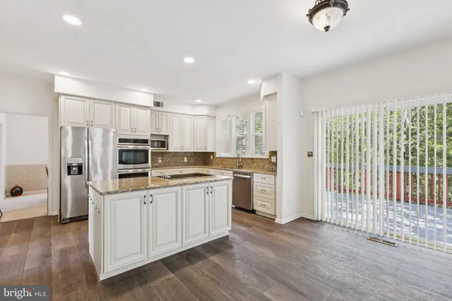 a kitchen with kitchen island white cabinets and refrigerator