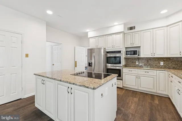 a kitchen with granite countertop white cabinets and refrigerator