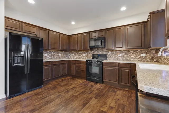 a kitchen with stainless steel appliances granite countertop a refrigerator stove top oven and sink