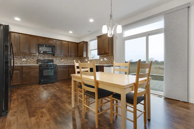 a dining room with stainless steel appliances kitchen island granite countertop a dining table chairs and granite counter top