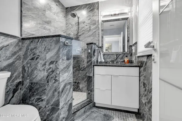a bathroom with a granite countertop sink a toilet and a mirror