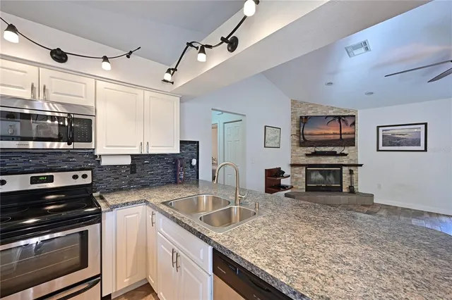 a kitchen with stainless steel appliances granite countertop a sink dishwasher stove and microwave with wooden floor