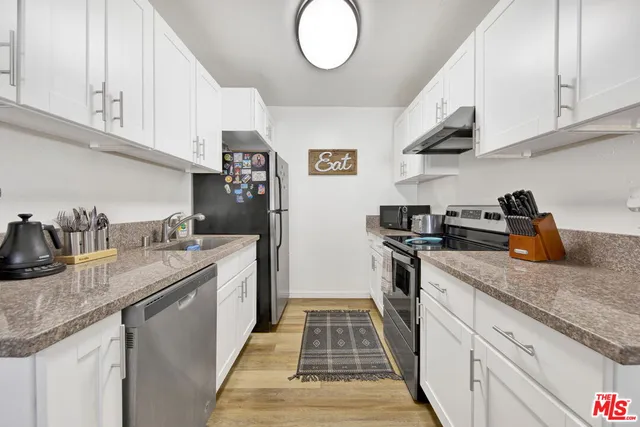 a kitchen with granite countertop stainless steel appliances a sink a stove and cabinets