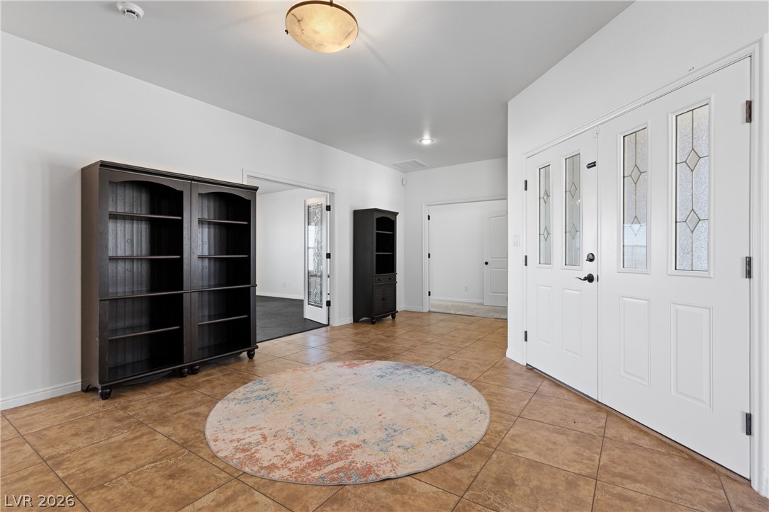 575 Gann Avenue Logandale, NV 89021 - Photo 7 of 75 A well-lit entry with tiled flooring, featuring a statement circular rug and decorative glass doors.