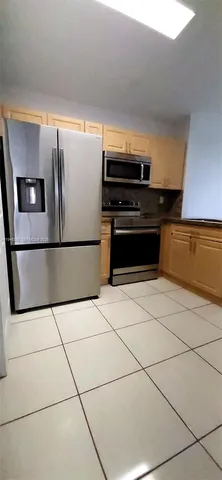 a kitchen with granite countertop a refrigerator and a stove top oven