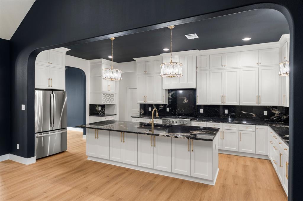 320 Dalton Road Canton, TX 75103 - Photo 10 of 29 Kitchen with arched walkways, freestanding refrigerator, a center island with sink, backsplash, and dark stone countertops