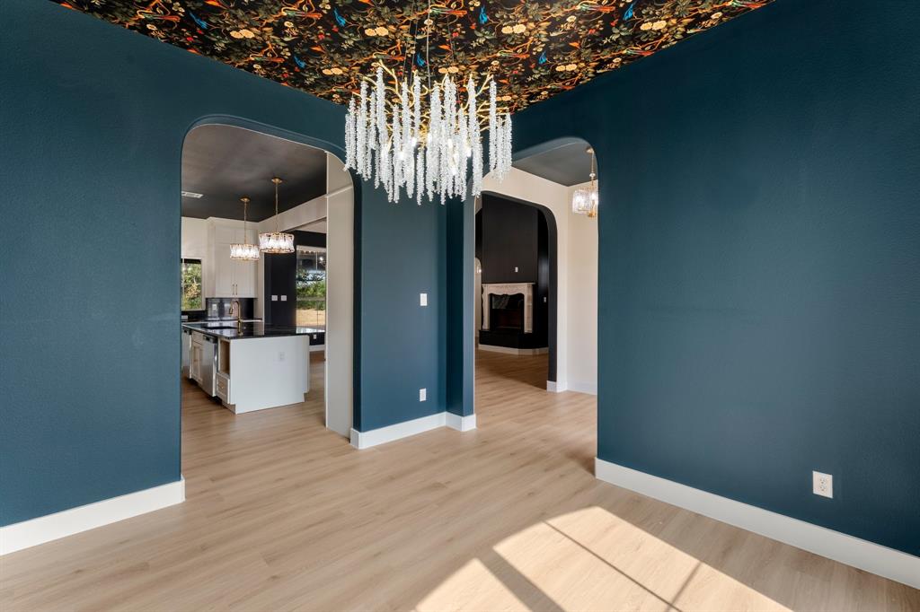 320 Dalton Road Canton, TX 75103 - Photo 8 of 29 Unfurnished dining area featuring a chandelier, light wood-style flooring, a fireplace, and arched walkways