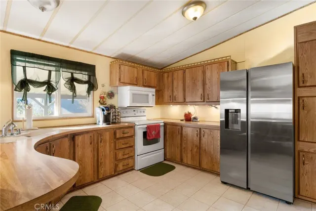 a kitchen with stainless steel appliances granite countertop a refrigerator a sink dishwasher a stove with wooden cabinets and floor