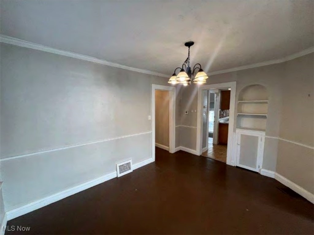 3579 Riedham Road Cleveland, OH 44120 - Photo 2 of 13 Unfurnished dining area featuring ornamental molding, dark wood-type flooring, built in features, and a chandelier