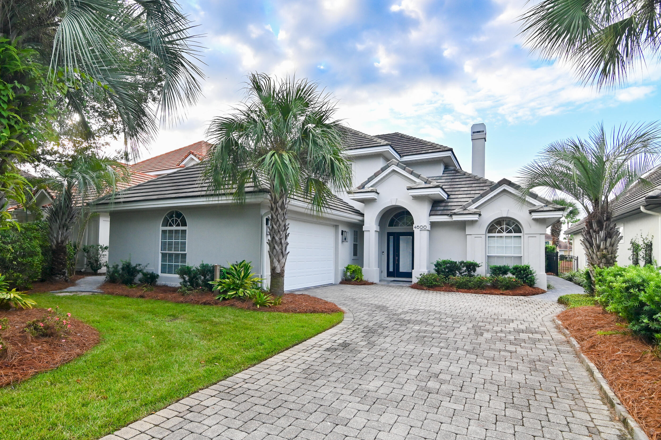 a front view of a house with a garden and palm trees