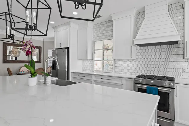 a kitchen with stainless steel appliances a sink a stove cabinets and a window