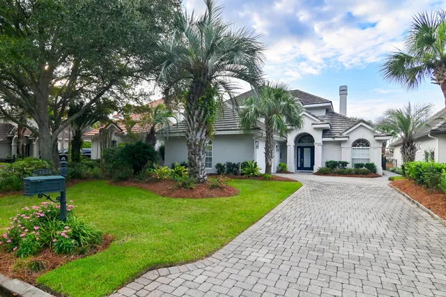 a front view of a house with garden and trees