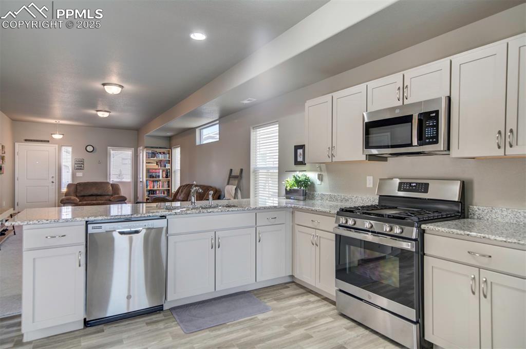 4151 Jericho Loop Colorado Springs, CO 80916 - Photo 12 of 34 a kitchen with white cabinets stainless steel appliances and sink