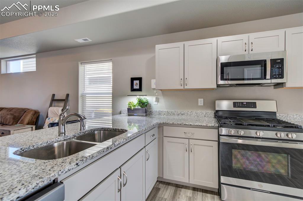 4151 Jericho Loop Colorado Springs, CO 80916 - Photo 15 of 34 a kitchen with white cabinets a sink and appliances