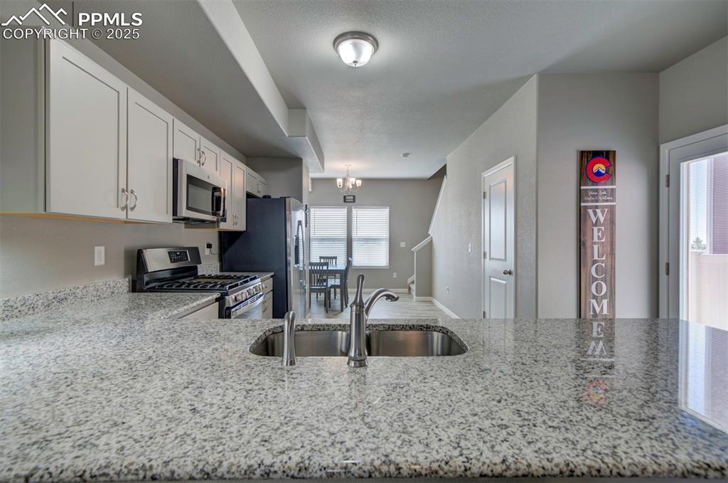 4151 Jericho Loop Colorado Springs, CO 80916 - Photo 9 of 34 a kitchen with stainless steel appliances granite countertop a sink a stove and a refrigerator