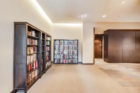 a view of an empty room with bookshelf and a window