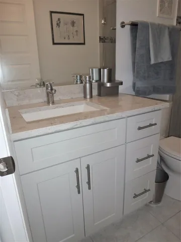 a bathroom with a granite countertop sink a toilet and a mirror